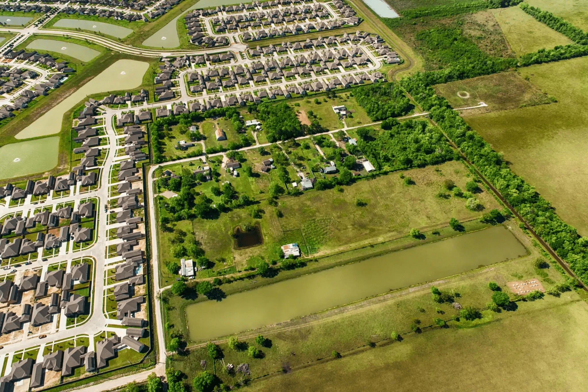 Aerial view of a suburban neighborhood adjacent to open green fields.